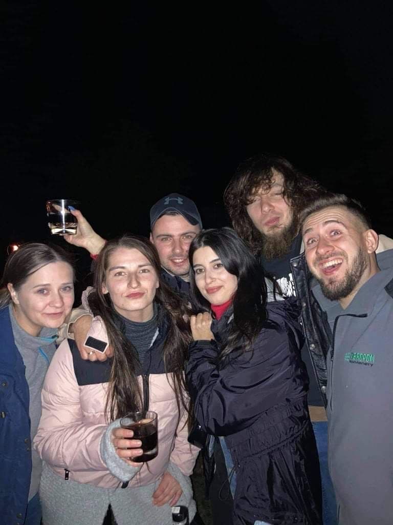 Nocne zdjęcie z fleszem — szóstka znajomych w szerokich uśmiechach